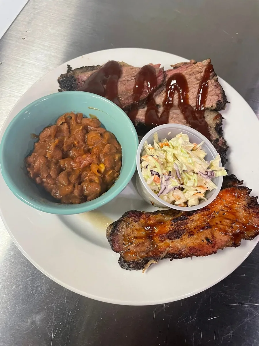 Barbecue plate with sliced smoked meat, beans, and slaw